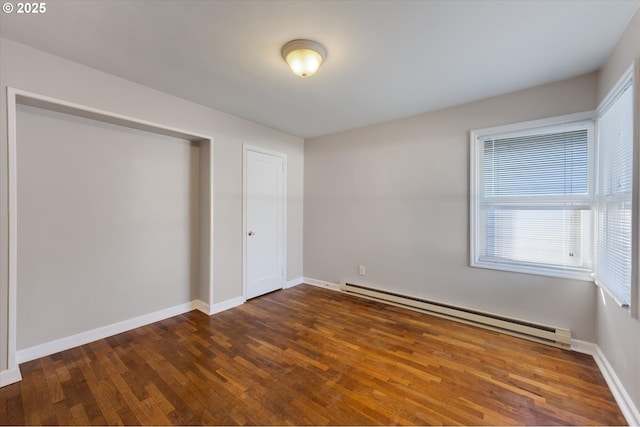 unfurnished bedroom with dark hardwood / wood-style flooring and a baseboard heating unit