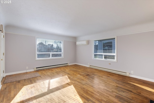 unfurnished room with hardwood / wood-style floors, a baseboard heating unit, and a wall mounted AC