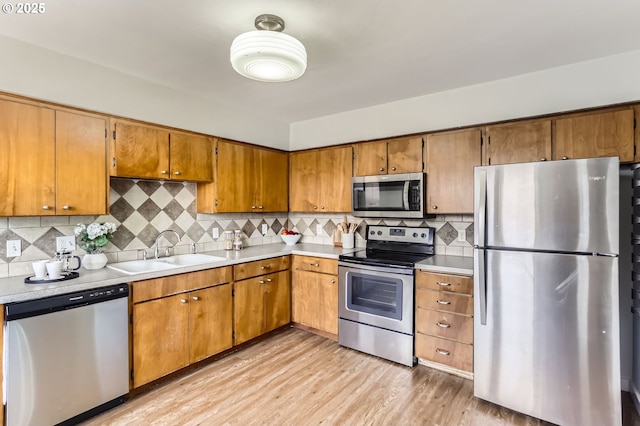kitchen featuring a sink, appliances with stainless steel finishes, light wood-style flooring, and light countertops