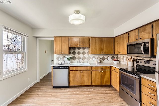 kitchen featuring a sink, appliances with stainless steel finishes, decorative backsplash, and light countertops