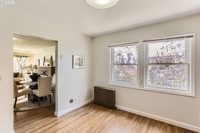 empty room featuring baseboards, radiator, and light wood-style floors