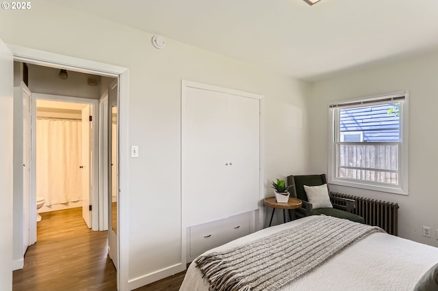bedroom featuring a closet, baseboards, radiator heating unit, and wood finished floors