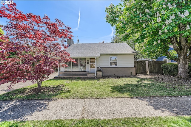 view of front of home with brick siding, a front lawn, fence, and a chimney