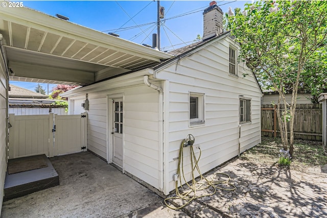 view of side of property with fence, a chimney, and a gate