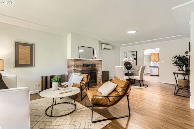 living area featuring a brick fireplace, an AC wall unit, radiator, baseboards, and wood finished floors