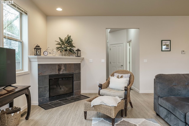 living room with a tiled fireplace and light hardwood / wood-style floors