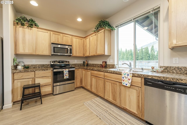 kitchen featuring stainless steel appliances, light brown cabinetry, sink, and light wood-type flooring