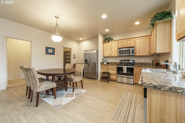 kitchen featuring sink, hanging light fixtures, light brown cabinets, light wood-type flooring, and appliances with stainless steel finishes