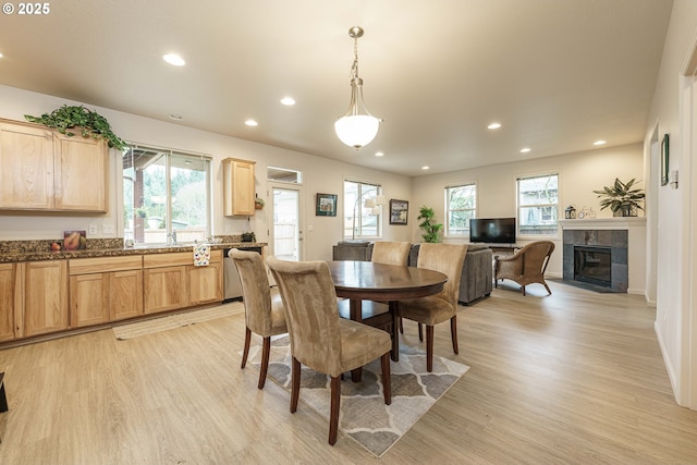 dining room with a tile fireplace, plenty of natural light, and light hardwood / wood-style floors