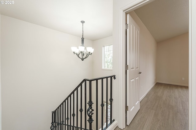 stairway with hardwood / wood-style floors and an inviting chandelier