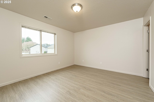 empty room with a textured ceiling and light wood-type flooring