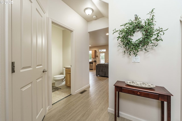 hallway featuring vaulted ceiling and light hardwood / wood-style flooring