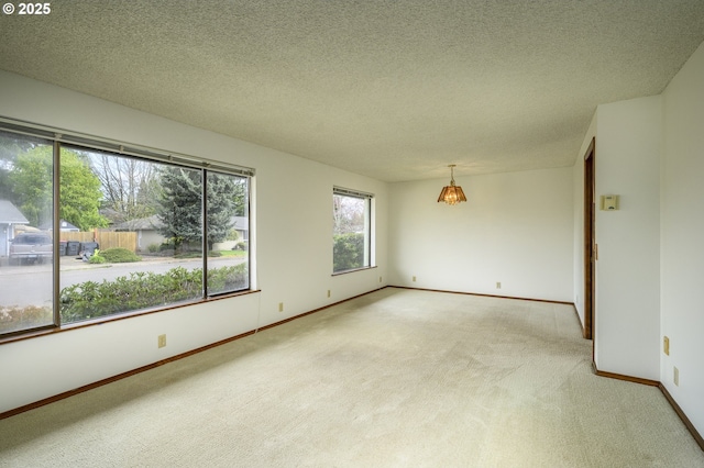 empty room featuring light carpet, baseboards, and a textured ceiling