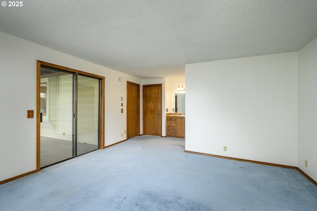 spare room with light carpet, baseboards, and a textured ceiling