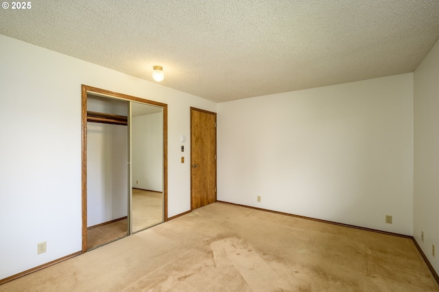 unfurnished bedroom with light carpet, baseboards, multiple closets, and a textured ceiling
