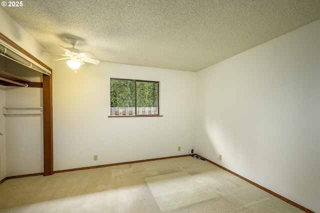 unfurnished bedroom with a textured ceiling, a closet, light colored carpet, and a ceiling fan