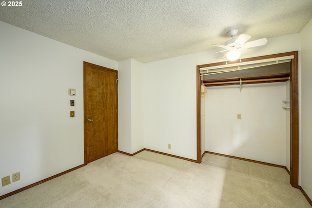 unfurnished bedroom with a closet, ceiling fan, light colored carpet, and a textured ceiling