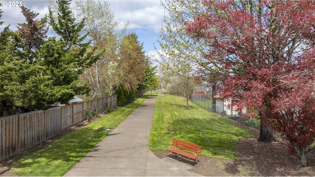 view of home's community with fence and a lawn