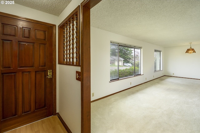 entrance foyer featuring a textured ceiling, baseboards, and light carpet