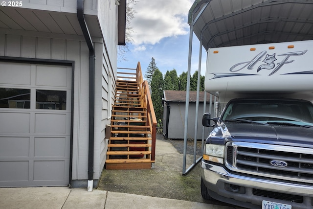 view of parking with a garage, stairway, and a detached carport