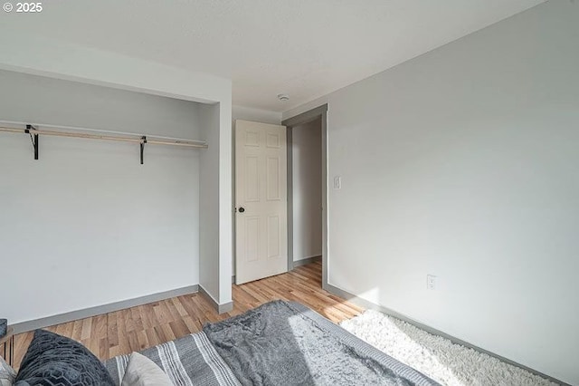 unfurnished bedroom with baseboards, wood finished floors, and a closet