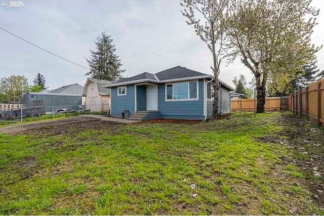 back of house with a fenced backyard and a lawn