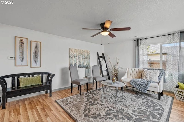sitting room featuring light wood-type flooring, a textured ceiling, and ceiling fan