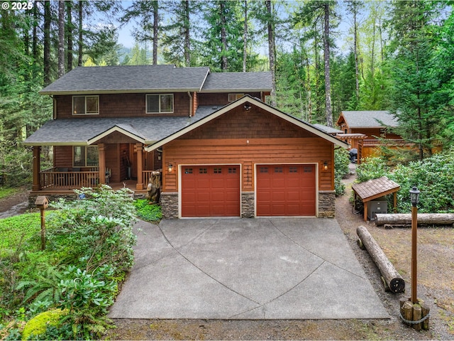 chalet / cabin featuring a porch, driveway, stone siding, and a garage