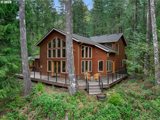 rear view of house featuring a wooden deck and a wooded view