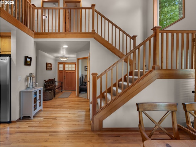foyer featuring light wood-style floors, stairs, and a towering ceiling
