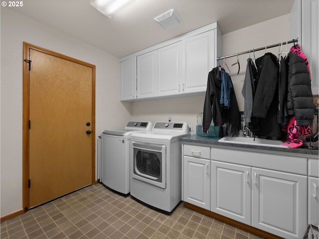 washroom with visible vents, light floors, washing machine and clothes dryer, a sink, and cabinet space