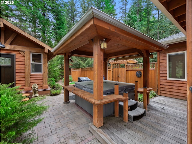 view of patio / terrace with fence, a covered hot tub, a wooden deck, and a gazebo