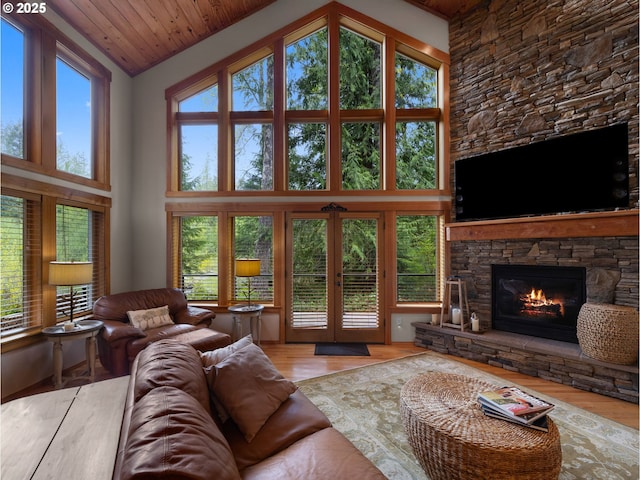living room with a stone fireplace, wood ceiling, wood finished floors, and high vaulted ceiling
