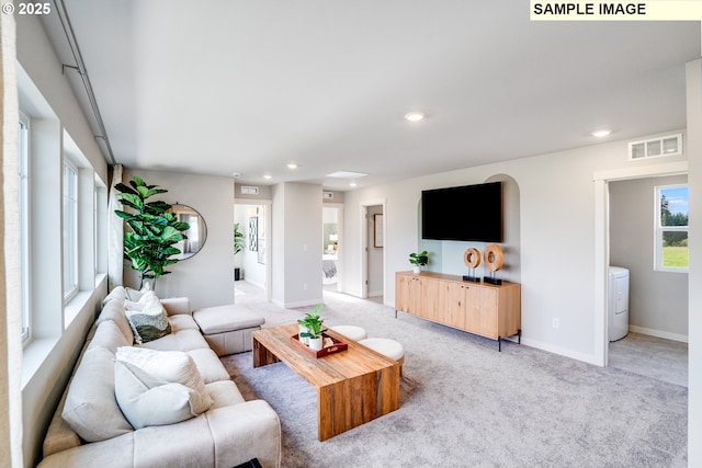 living area with washer / clothes dryer, recessed lighting, light colored carpet, and baseboards