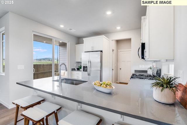 kitchen with stainless steel appliances, a sink, a peninsula, recessed lighting, and white cabinets
