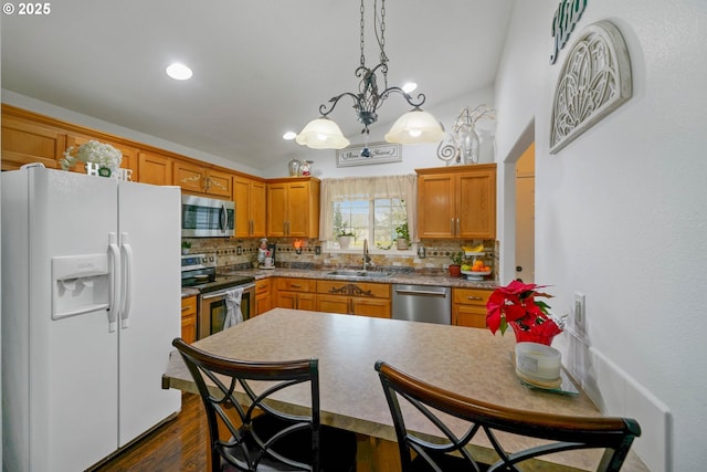 kitchen featuring sink, appliances with stainless steel finishes, hanging light fixtures, dark hardwood / wood-style floors, and tasteful backsplash