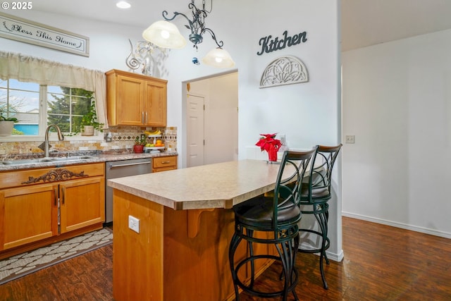 kitchen with sink, hanging light fixtures, a kitchen island, dark hardwood / wood-style flooring, and stainless steel dishwasher