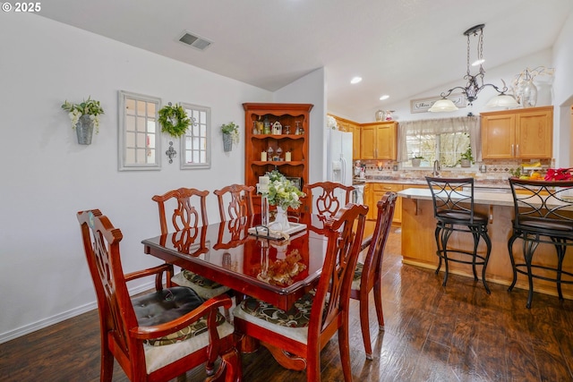 dining space with an inviting chandelier, dark hardwood / wood-style floors, and vaulted ceiling