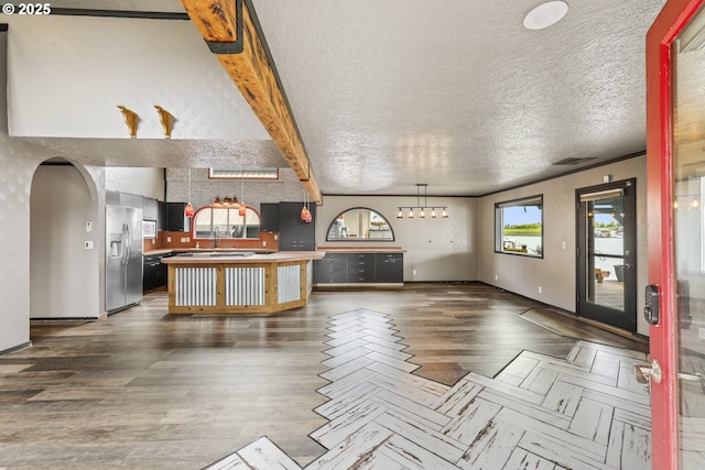 2039 N Jantzen Ave, Portland, OR 97217 - unfurnished living room featuring a textured ceiling, baseboards, a sink, wood finished floors, and arched walkways