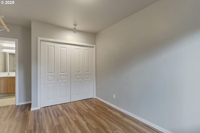 unfurnished bedroom featuring sink, a closet, and light hardwood / wood-style flooring