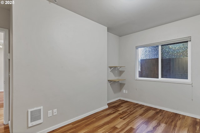 empty room featuring heating unit and light hardwood / wood-style floors