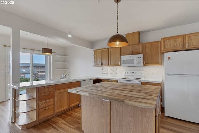 kitchen featuring a kitchen island, hanging light fixtures, white appliances, kitchen peninsula, and light wood-type flooring