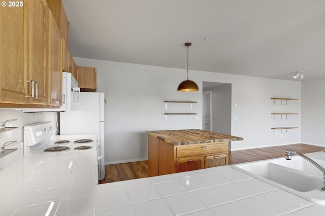 kitchen featuring sink, white appliances, tile counters, decorative light fixtures, and kitchen peninsula