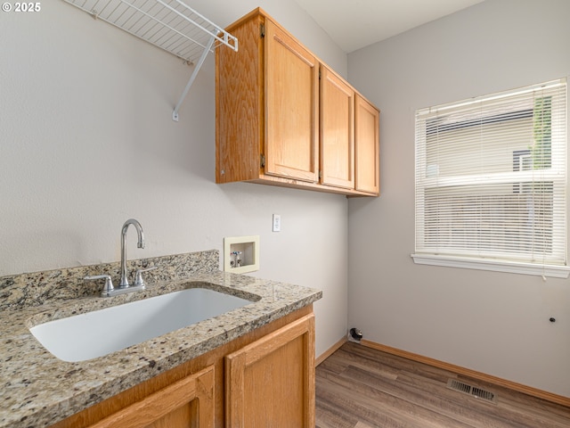 washroom with cabinet space, washer hookup, a sink, wood finished floors, and visible vents