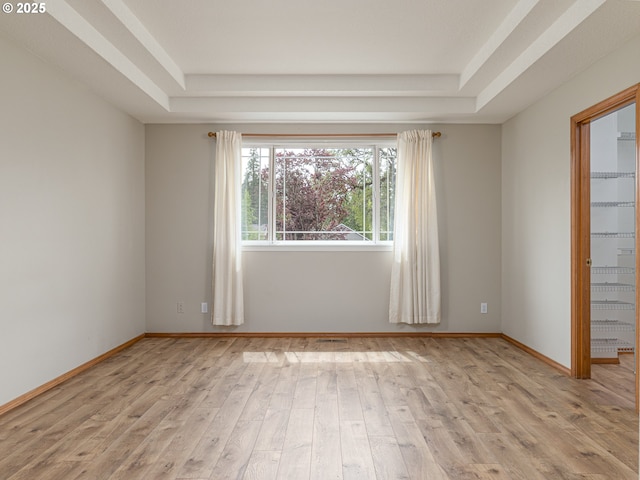 spare room featuring baseboards, a tray ceiling, and wood finished floors