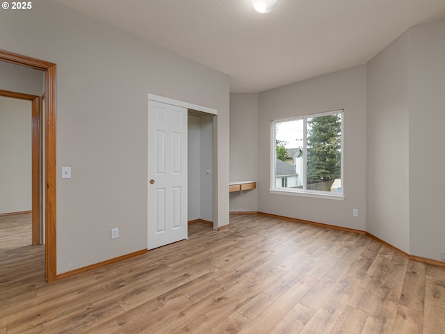 unfurnished bedroom with light wood-type flooring, baseboards, and a closet