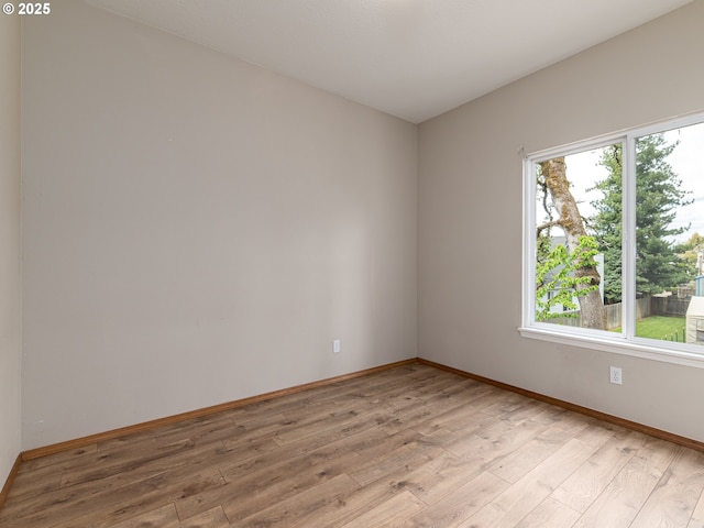 unfurnished room with baseboards and light wood-style flooring