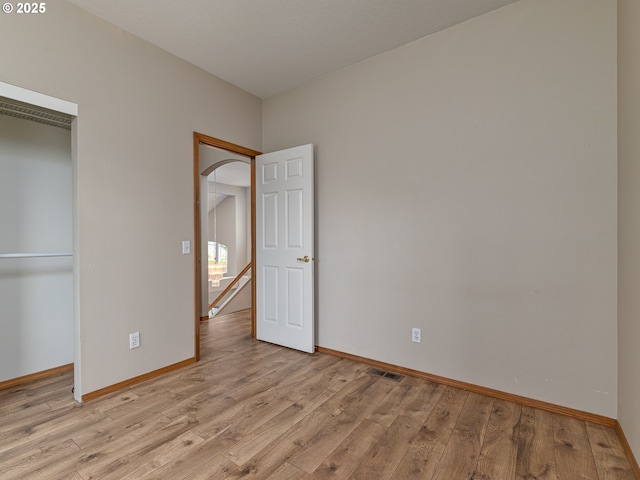unfurnished bedroom featuring light wood-type flooring, baseboards, visible vents, and a closet