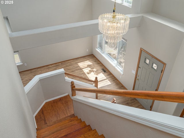 stairway with an inviting chandelier, wood finished floors, and visible vents