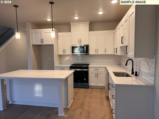 kitchen featuring white cabinetry, sink, pendant lighting, and stainless steel appliances